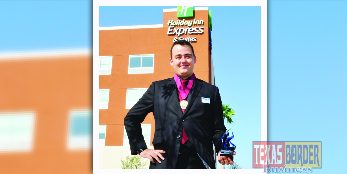 Kerry Martin, the General Manager for the Holiday Inn Express and Suites Edinburg holds the distinguish award; behind him the hotel building that has brought excellent reviews.