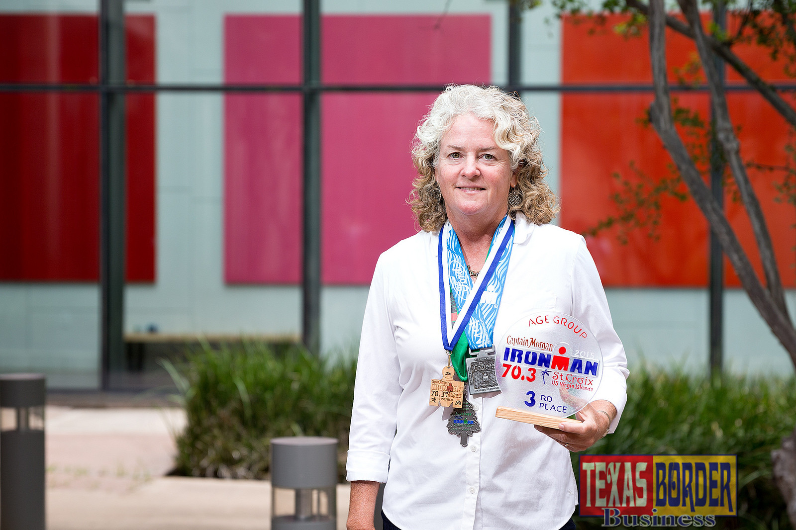 Dr. Karen Watt, a professor in the UTRGV Department of Organization and School Leadership, is currently in training for her third full Ironman Triathlon competition on Nov. 5 in Florida. Seen here on the UTRGV Edinburg Campus, she is holding awards and medals from her first two Ironman Triathlons. (UTRGV Photo by Paul Chouy)