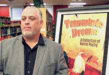 Author Roberto Rocha stands in front of a poster of his book “Tamarindo Dreams: A Collection of Barrio Poetry,” while visiting with students at Edinburg High School.  