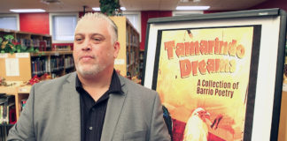 Author Roberto Rocha stands in front of a poster of his book “Tamarindo Dreams: A Collection of Barrio Poetry,” while visiting with students at Edinburg High School.  