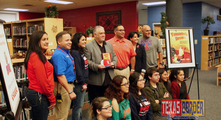 Author Roberto Rocha (center) holds his book “Tamarindo Dreams: A Collection of Barrio Poetry,” while posing for a photo with students, staff and classmates at Edinburg High School.